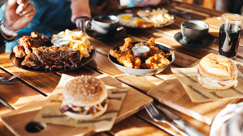 Sandwiches, ribs, and wings on a rustic wooden table.