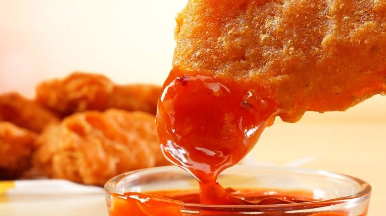 A McDonald's Spicy Chicken Nugget being dipped into Mighty Hot Sauce.
