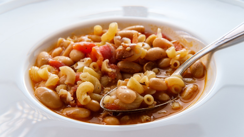 close-up shot of pasta e fagioli in white bowl with a spoon