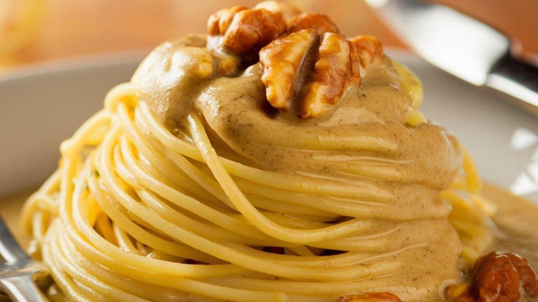 pasta with salsa di noci on white plate with a fork