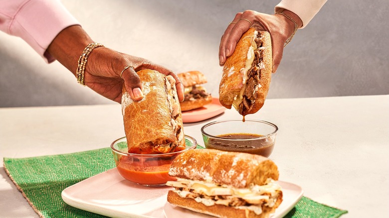 People dipping toasted Panera Bread sandwiches into sauce