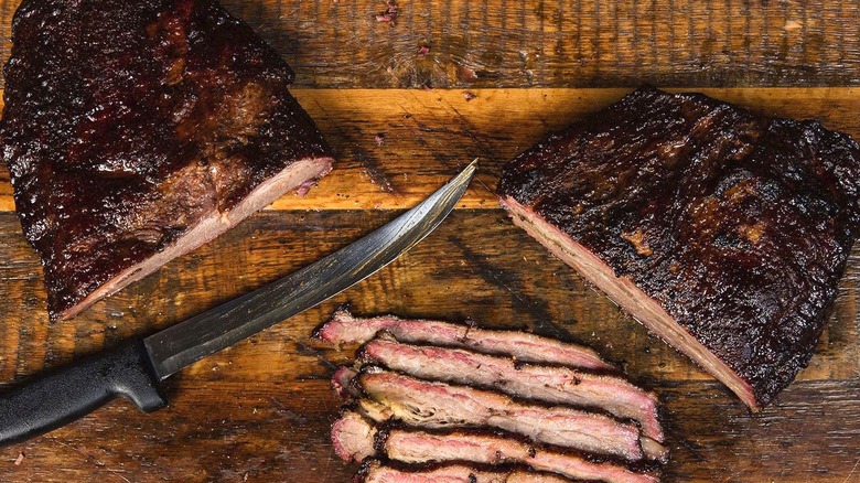 Dinosaur BBQ's brisket on wooden surface with knife