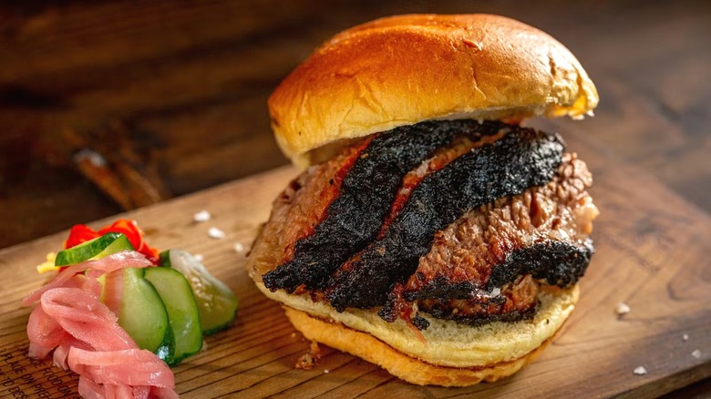 Mighty Quinn's brisket sandwich and pickles on cutting board