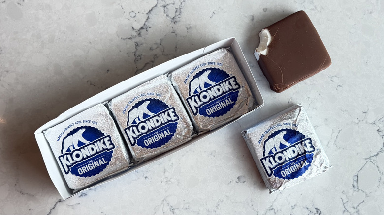 A Klondike The Original Ice Cream Bar with a bite taken out of it sits next to its package