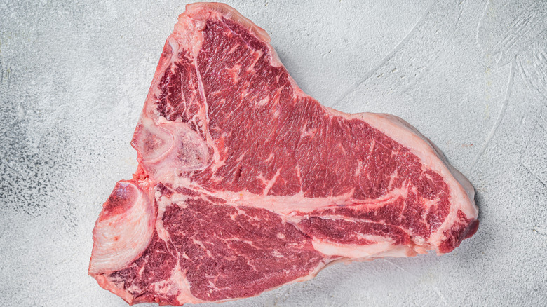 raw Chicago porterhouse steak cut on stainless steel table
