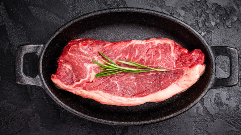 Kansas strip steak in a cast-iron skillet with a sprig of rosemary