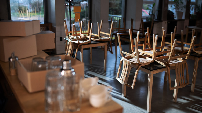 Cardboard boxes sitting on a bar in a closed restaurant with chairs placed onto tabletops
