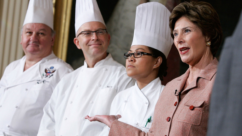 Laura Bush introduces three White House chefs with a gesture, one woman and two men