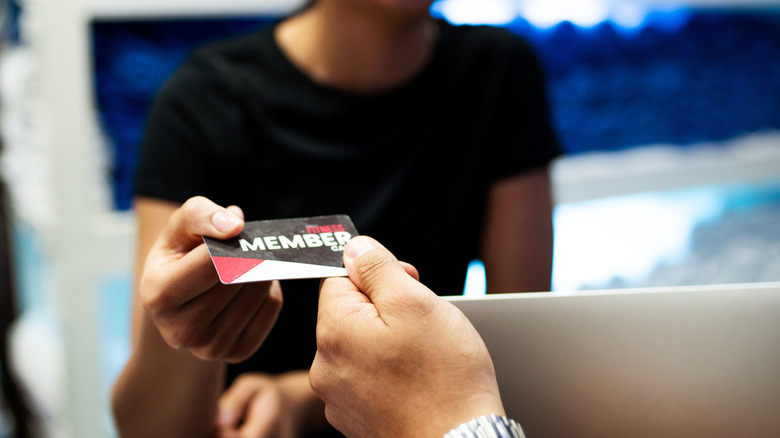 Two hands exchanging a card that says member