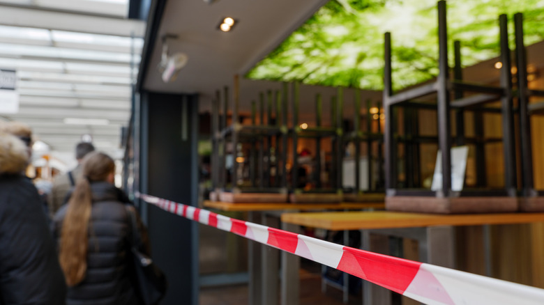 People standing outside of closed restaurant
