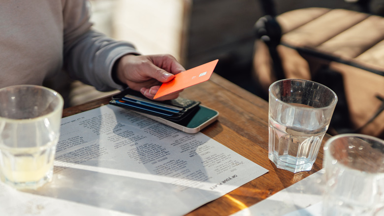 Person preparing credit card for payment at restaurant