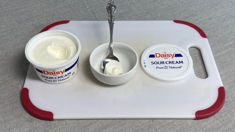 Sour cream in a spoon alongside the packaging