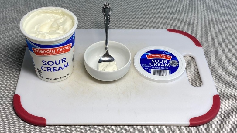 Sour cream in a spoon alongside the packaging