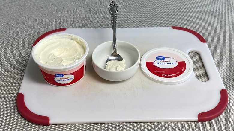 Sour cream in a spoon alongside the packaging