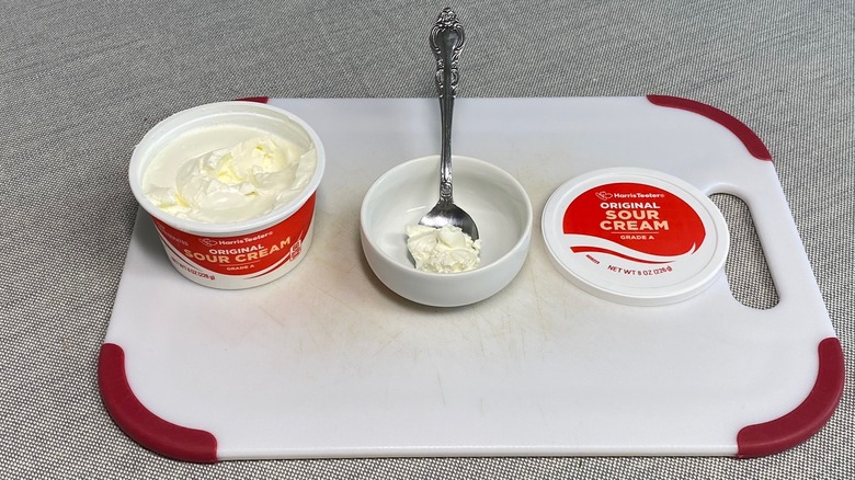 Sour cream in a spoon alongside the packaging