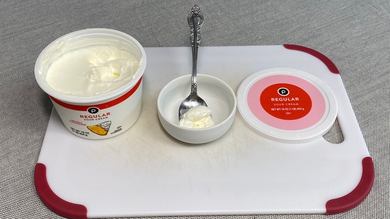 Sour cream in a spoon alongside the packaging