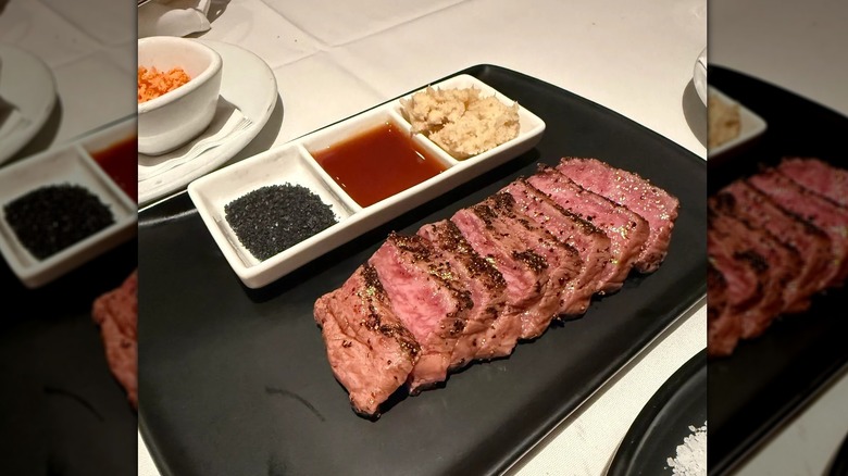 Slices of steak with sauce options in a dish next to it