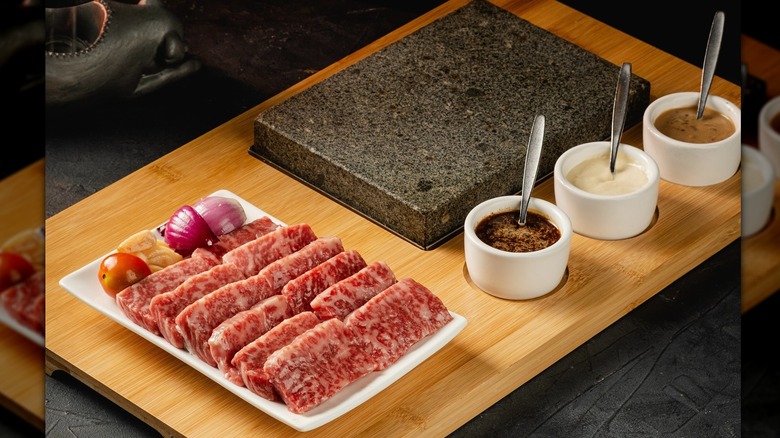 Wagyu steak on a wood board with sauces in bowls