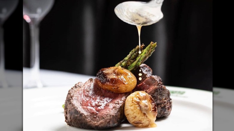 Steak with onions and asparagus and sauce dribbled on it