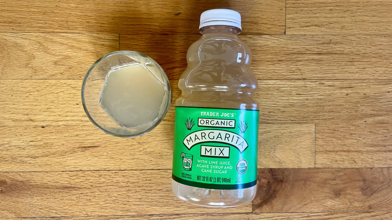Overhead view of a bottle and glass of Trader Joe's Organic Margarita Mix on a wooden background