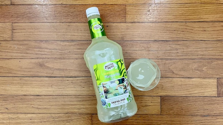 Overhead view of bottle and glass of Master Of Mixes Handcrafted Margarita Mixer on a wooden background