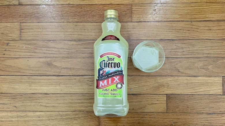 Overhead view of a bottle and glass of Jose Cuervo Classic Margarita Mix on a wooden background