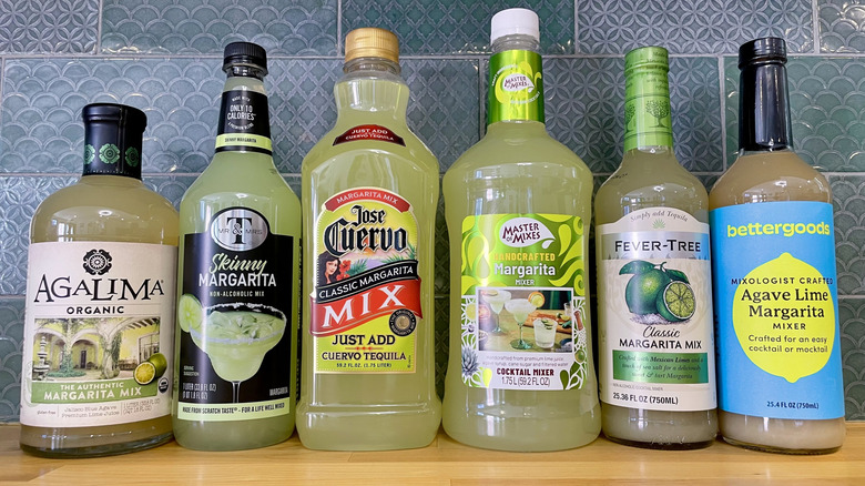 Collection of various margarita mix bottles on a wooden counter top