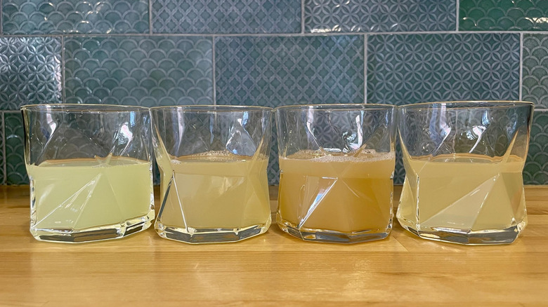 Four glasses of various margarita mixes on a wooden counter top