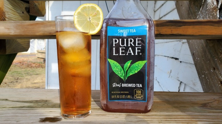 A bottle of Pure Leaf sweet tea next to a tall glass of tea with ice and a slice of lemon