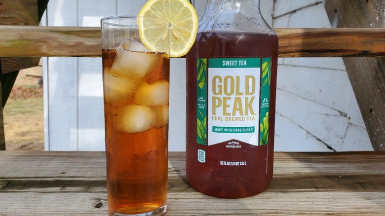 A bottle of Gold Peak sweet tea next to a tall glass of tea with ice and a slice of lemon