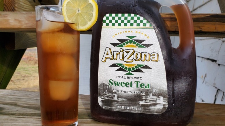 A bottle of Arizona sweet tea next to a tall glass of tea with ice and a slice of lemon