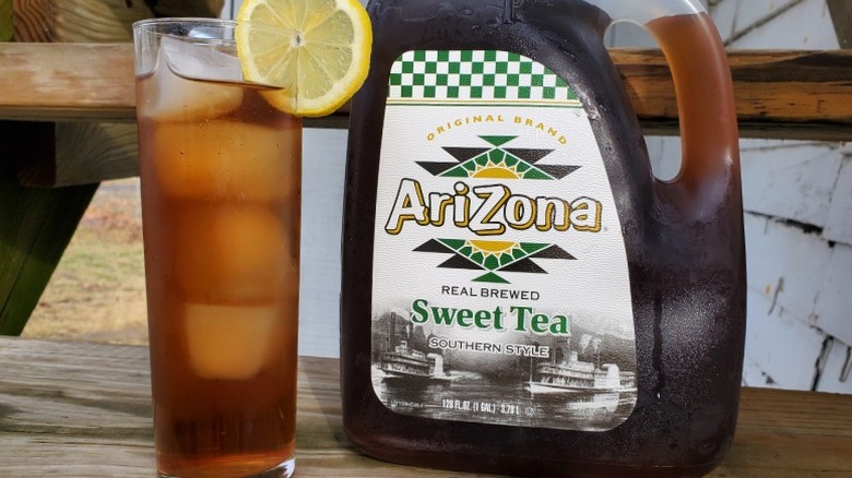 A bottle of Arizona sweet tea next to a tall glass of tea with ice and a slice of lemon