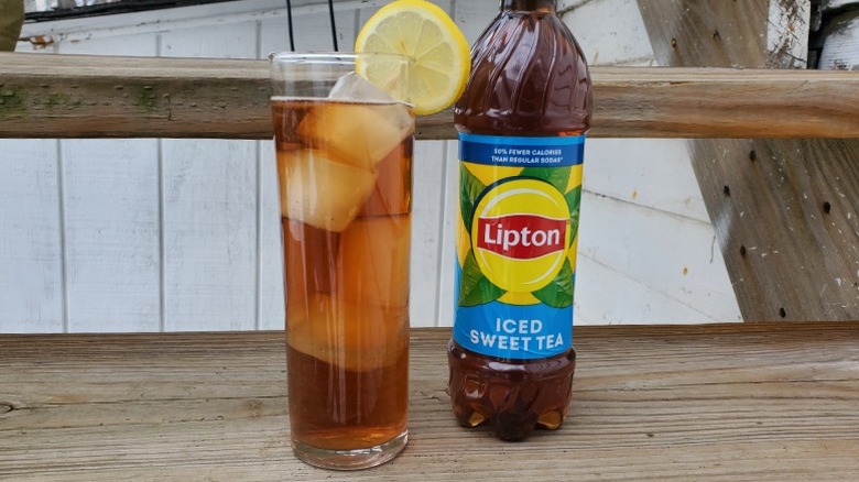 A bottle of Lipton sweet tea next to a tall glass of tea with ice and a slice of lemon