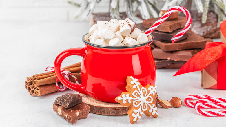 A mug of hot chocolate topped with marshmallows and a candy cane