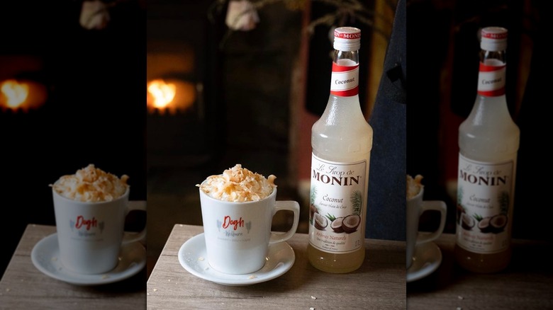 Hot chocolate topped with toasted, shredded coconut next to a bottle