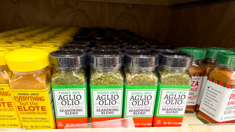 A shelf at Trader Joe's stocked with Aglio Olio, Everything but the Elote, and Pizza Sprinkle seasoning jars