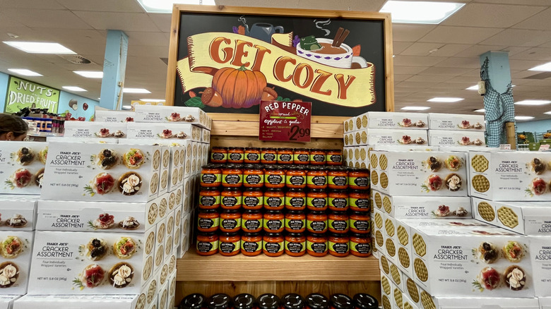 A Trader Joe's end display with a hand painted sign that says "Get Cozy" and features images of pumpkins and mulled wine