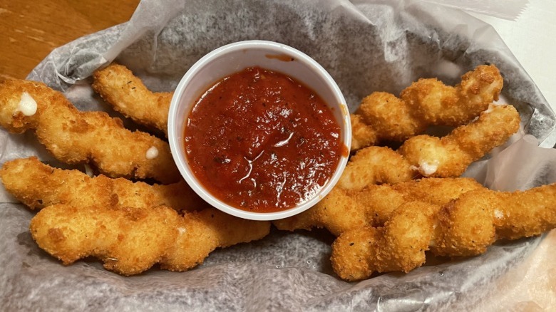 Twisted mozzarella sticks as a side with a pot of red dipping sauce