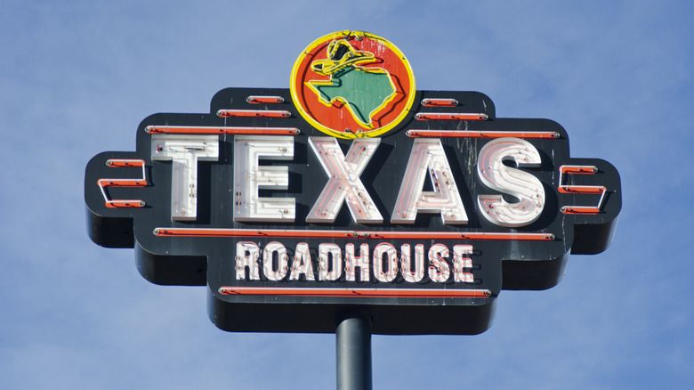 The sign outside a Texas Roadhouse with blue sky in the background