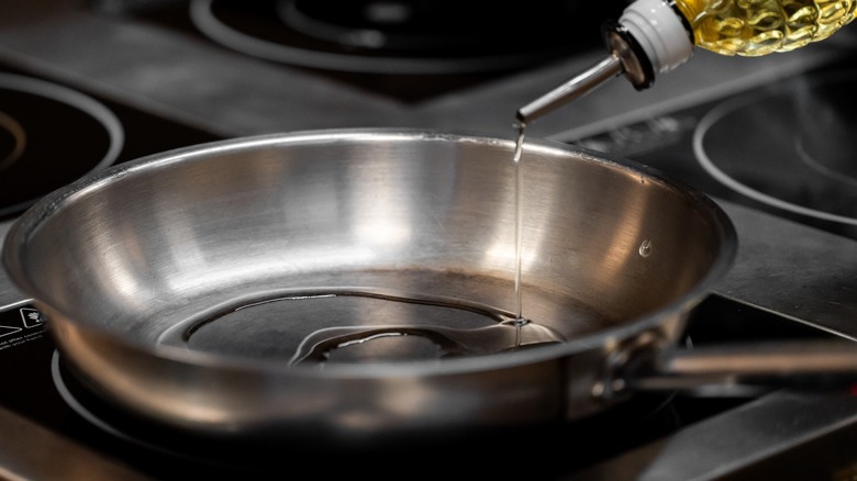Pouring oil into a stainless steel pan