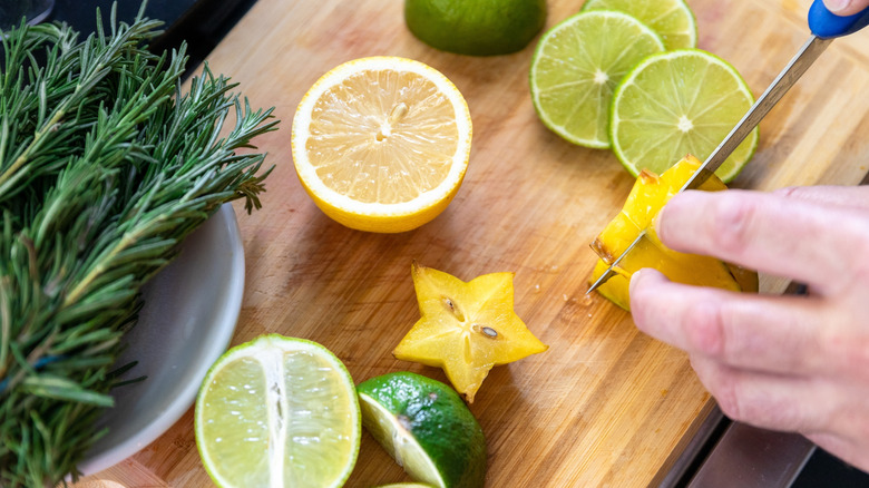 a person various slicing fruit over a wooden cutting board