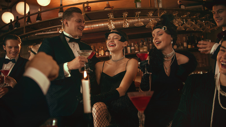 People dressed up in Roaring '20s clothes, drinking in a bar