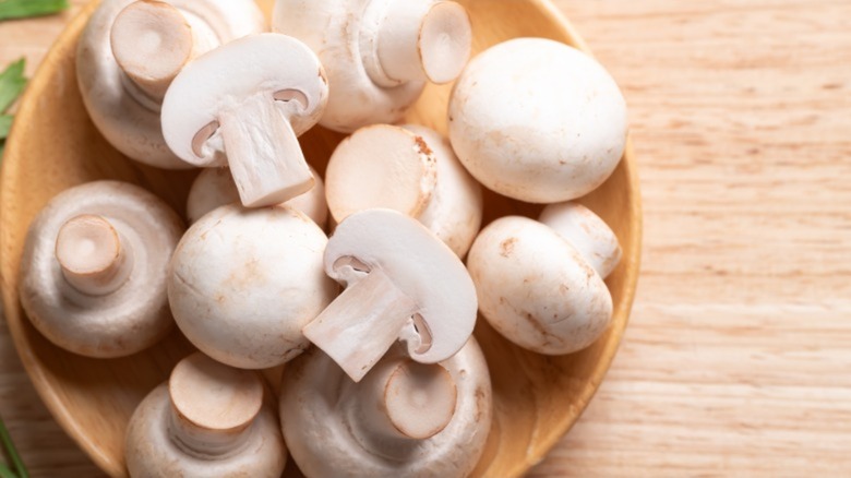 Raw button mushrooms in a wooden bowl