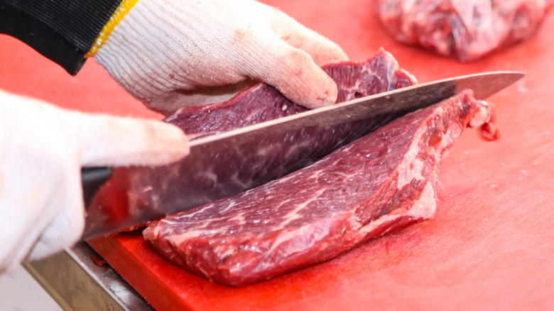 Butcher slicing chunk of meat on counter
