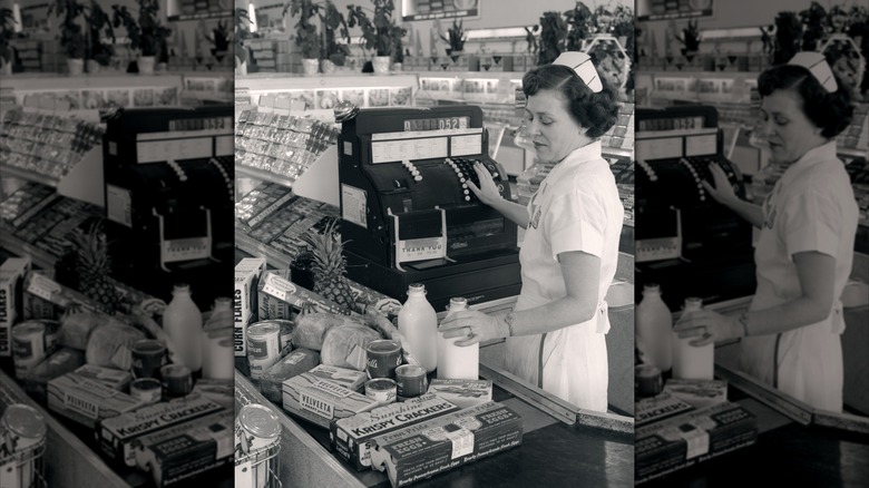 Cashier ringing up glass bottles of milk at a 1960s grocery store checkout lane