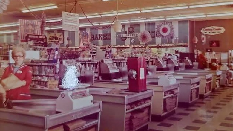 Checkout area of a 1960s grocery store with a coffee grinder at the end of one of the checkouts