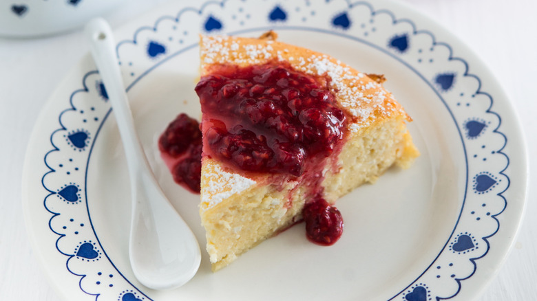a piece of Swedish cheesecake and raspberry jam on a white and blue plate