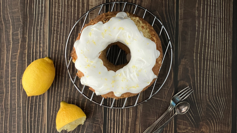a lemon cake with cottage cheese frosting on a wooden table surrounded by lemons