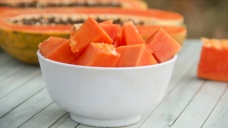 Papaya cubed in bowl with halved papaya in background