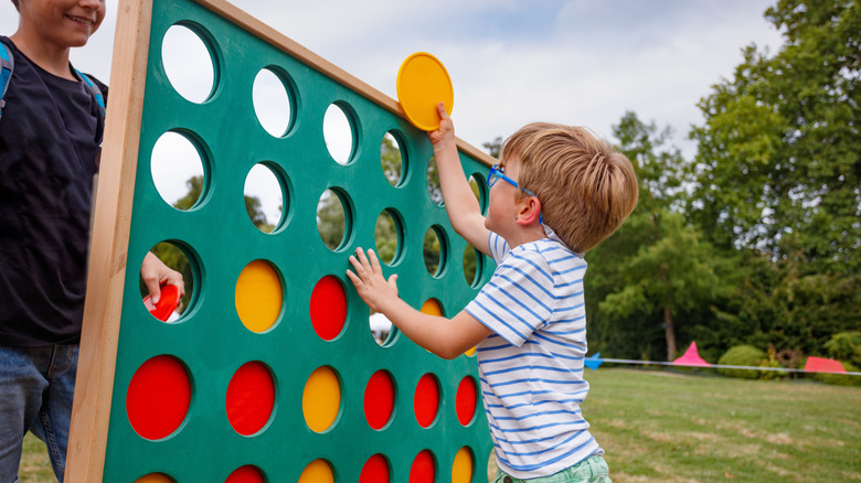 a kid smiles while playing giant connect four